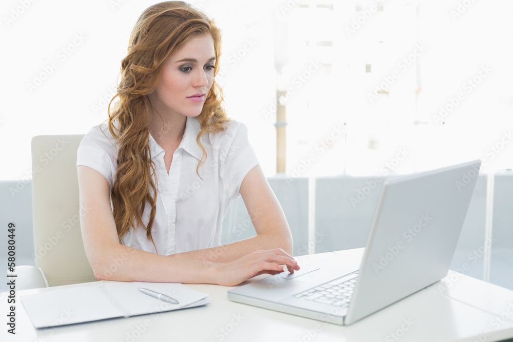 Serious businesswoman using laptop at office