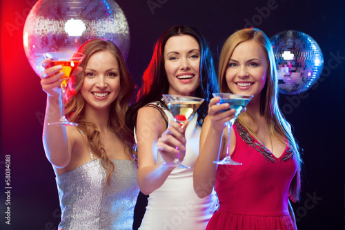 three smiling women with cocktails and disco ball