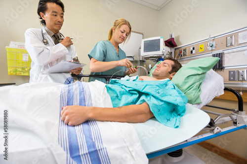 Doctor And Nurse Examining Patient In Hospital