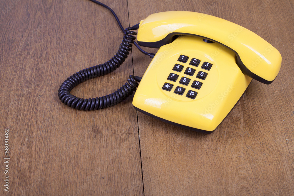 Retro yellow telephone on old wooden table background Retro yellow telephone on old wooden table background