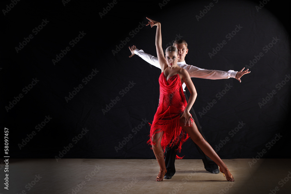 Latino dancers in ballroom against black background - obrazy, fototapety, plakaty 