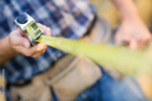 Fotografie Carpenter Holding Tape Measure Outdoors