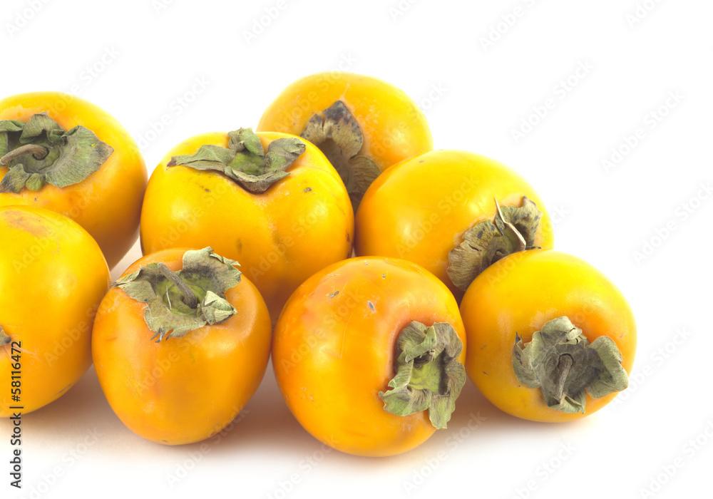 Heap of many ripe orange persimmons isolated closeup Heap of many ripe orange persimmons isolated closeup