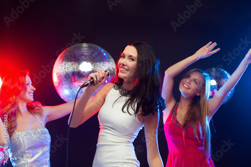 three smiling women dancing and singing karaoke © Syda Productions