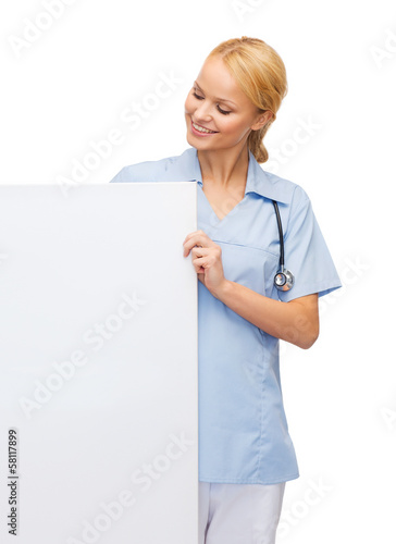 smiling female doctor or nurse with blank board