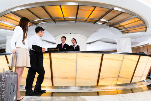 Photography Asian Chinese couple arriving at hotel front desk