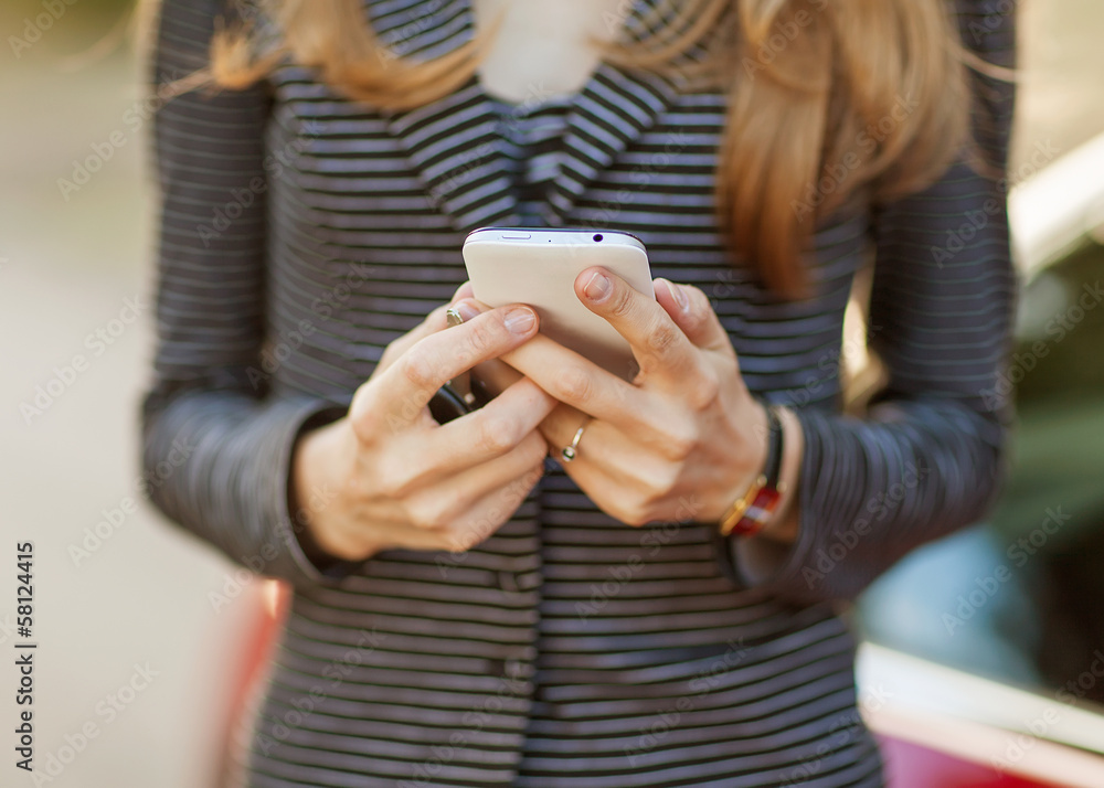 Fototapeta premium Young beautiful woman writes an SMS to your mobile phone.