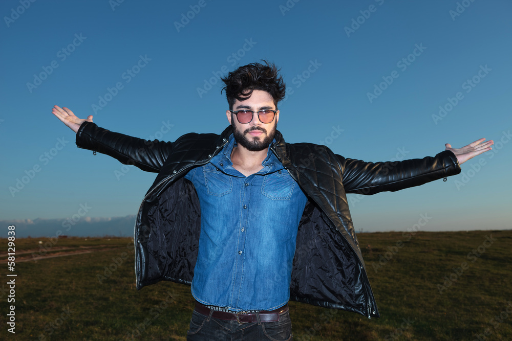 young man with open arms against blue sky