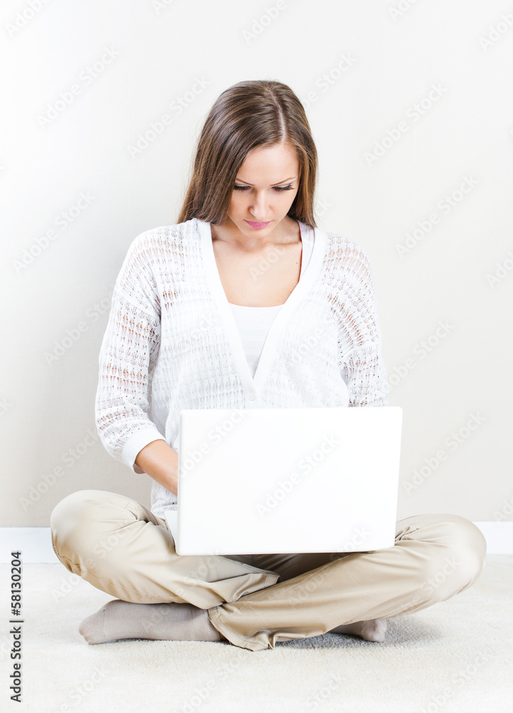 Naklejka premium Portrait of pretty happy young woman lying on floor with a lapto