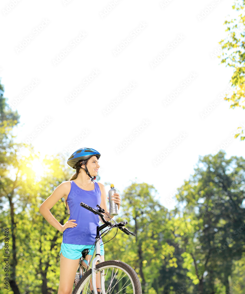 Naklejka premium Young female biker posing on a mountain bike on sunny day