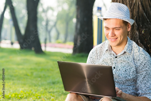 young man working in the park with a laptop © adam121