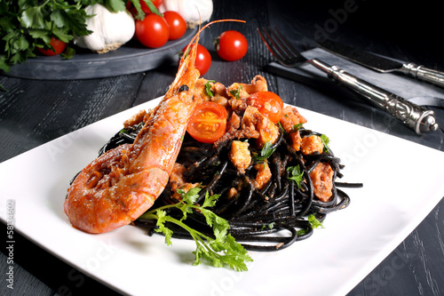 pasta nera con pesce e gamberi sfondo scuro photo