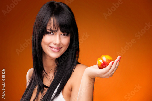 beautiful brunette woman with nectarine on orange background