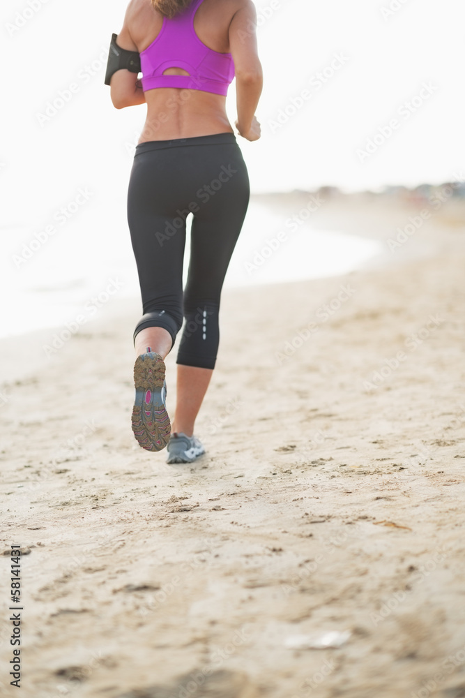 Naklejka premium Closeup on fitness woman running on the beach . rear view