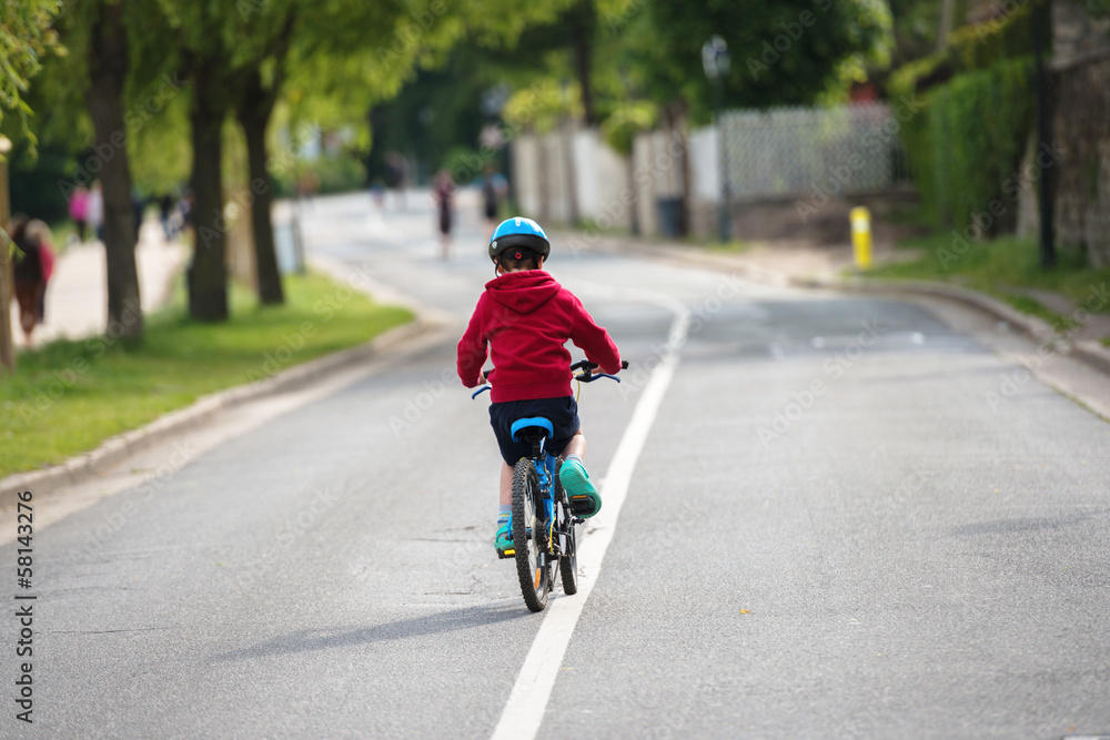 Obraz premium young child doing the bike alone in the middle of the road