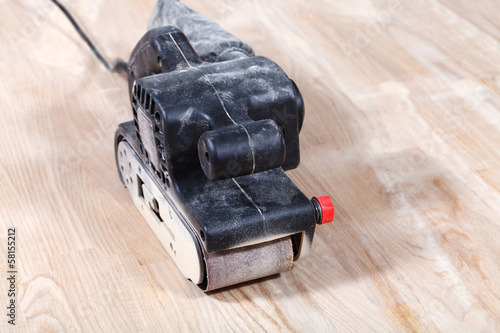 Obraz na plátně hand-held belt sander sanding wooden surface