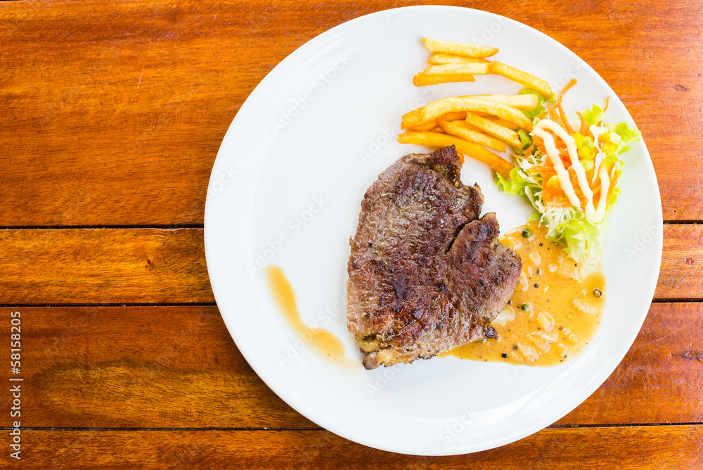 beef steak on white dish with salad and french fries