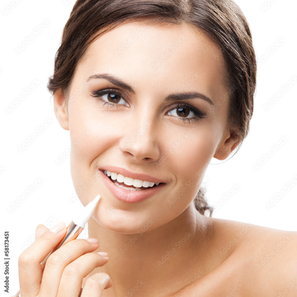 Smiling woman applying concealer on face, isolated Smiling woman applying concealer on face, isolated