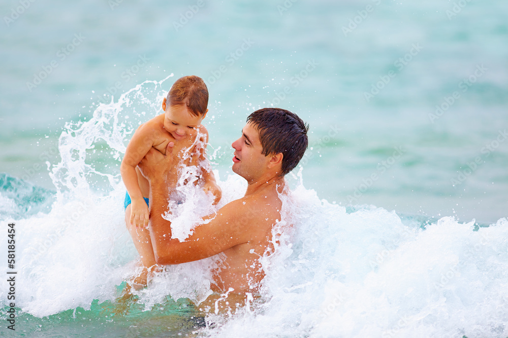 playful father and son having fun in water playful father and son having fun in water