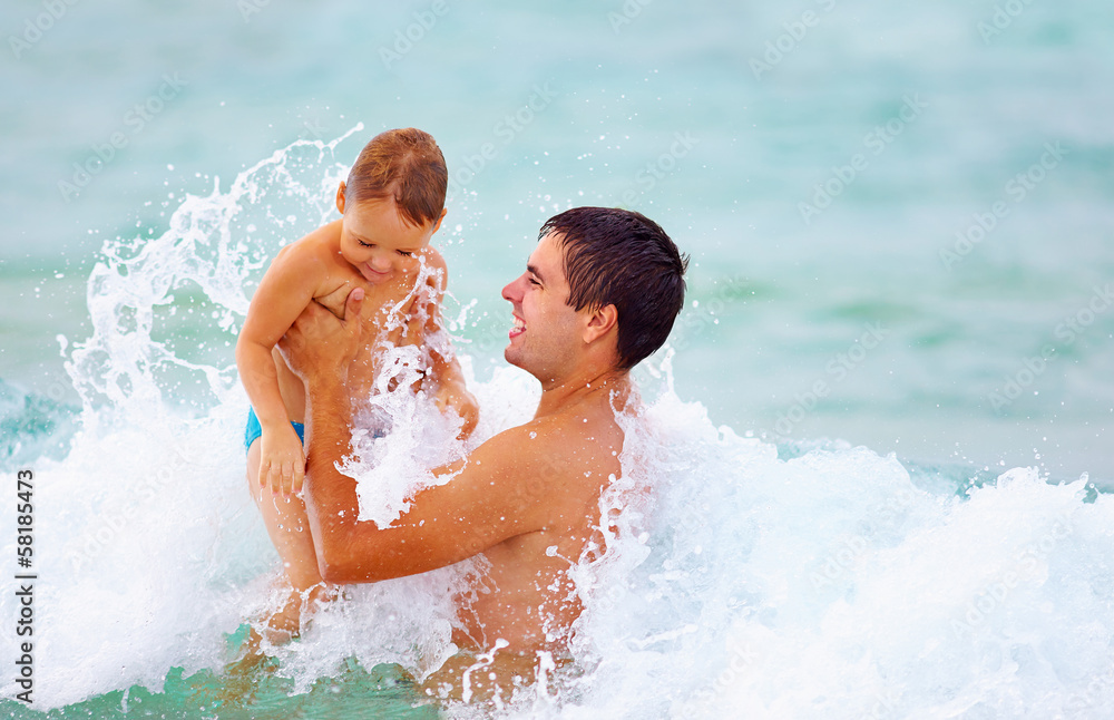 playful father and son having fun in water playful father and son having fun in water
