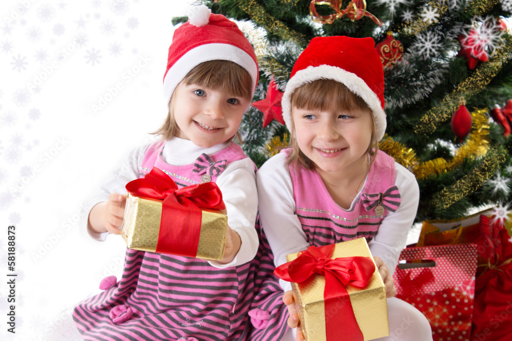 Little sisters with gifts under Christmas tree Little sisters with gifts under Christmas tree