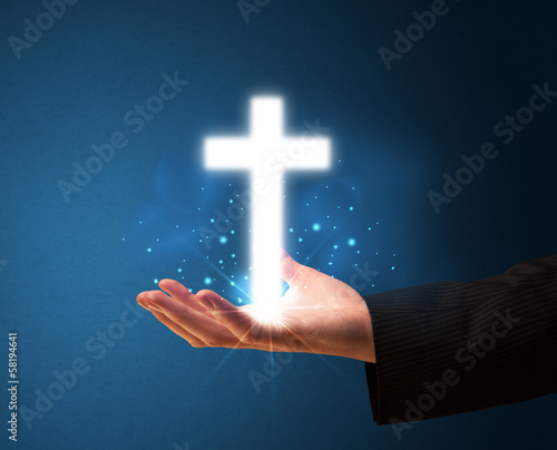 Glowing cross in the hand of a businessman