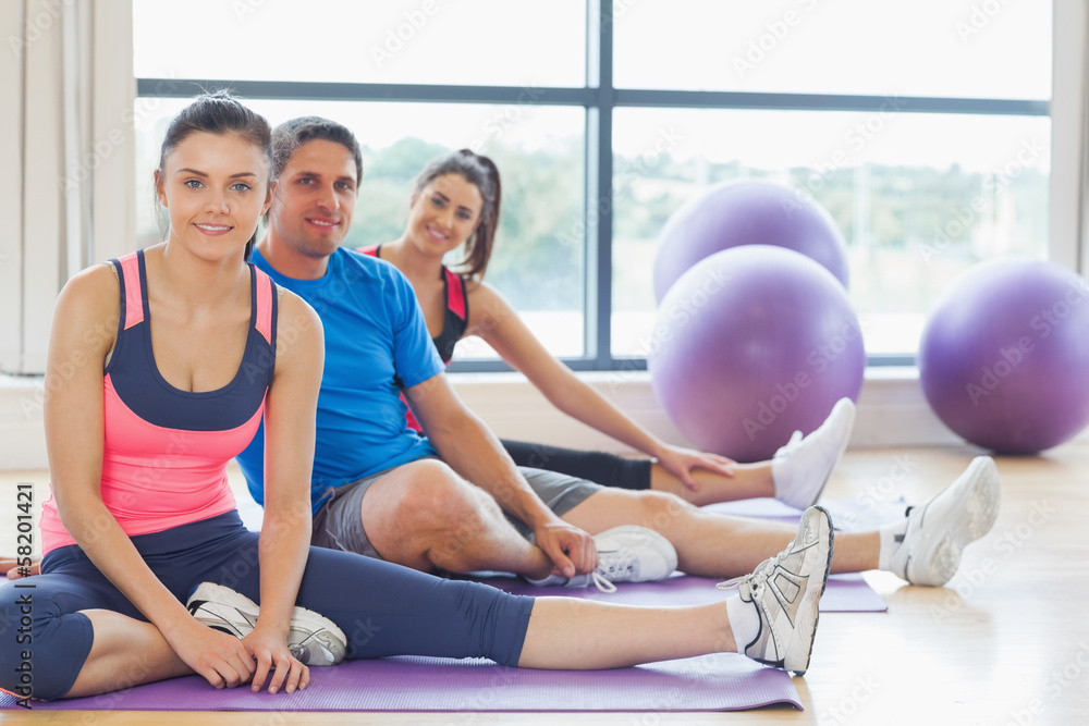 Fitness class and instructor sitting on exercise mats Fitness class and instructor sitting on exercise mats