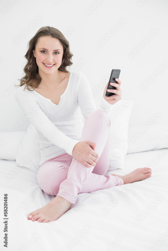 Smiling woman with mobile phone in bed Smiling woman with mobile phone in bed