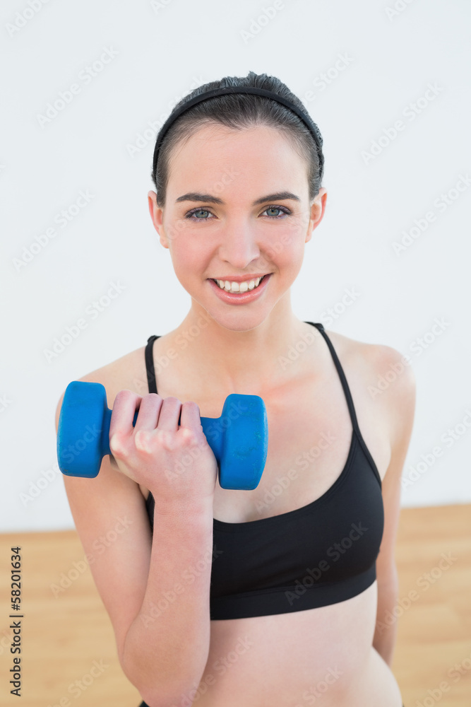 Smiling young woman with dumbbell at fitness studio Smiling young woman with dumbbell at fitness studio