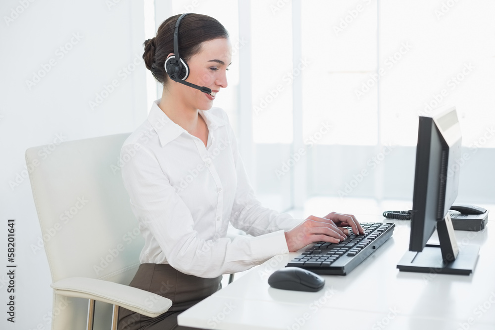 Businesswoman wearing headset while using computer Businesswoman wearing headset while using computer