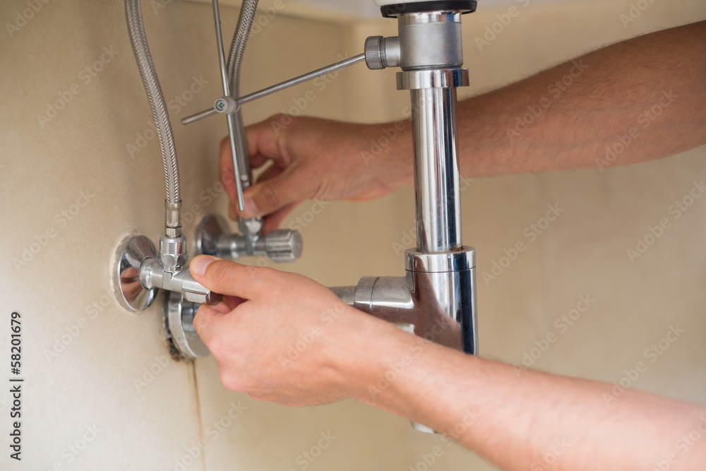 Extreme Close up of a plumber's hands and washbasin drain Extreme Close up of a plumber's hands and washbasin drain