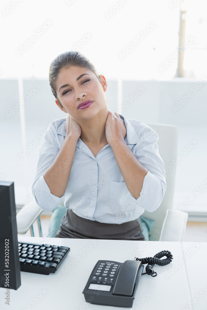 Businesswoman with neck pain in front of computer Businesswoman with neck pain in front of computer