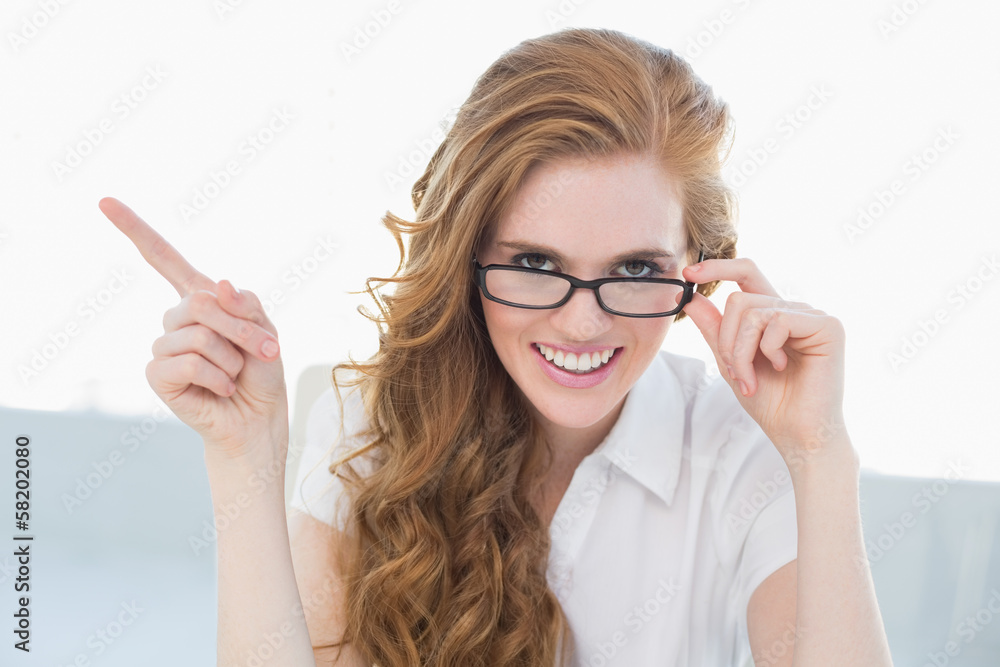 Cheerful businesswoman pointing to side in office