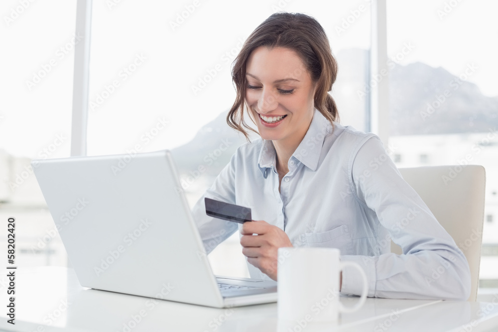 Smiling businesswoman doing online shopping in office Smiling businesswoman doing online shopping in office