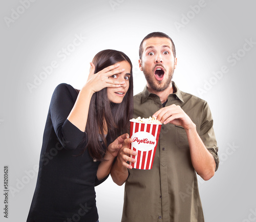 Young couple watching a movie and eating popcorn