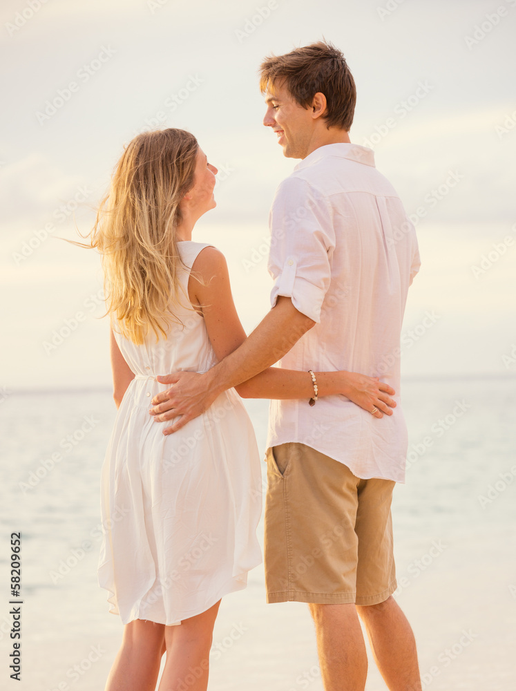 Happy romantic couple on the beach at sunset embracing each othe Happy romantic couple on the beach at sunset embracing each othe