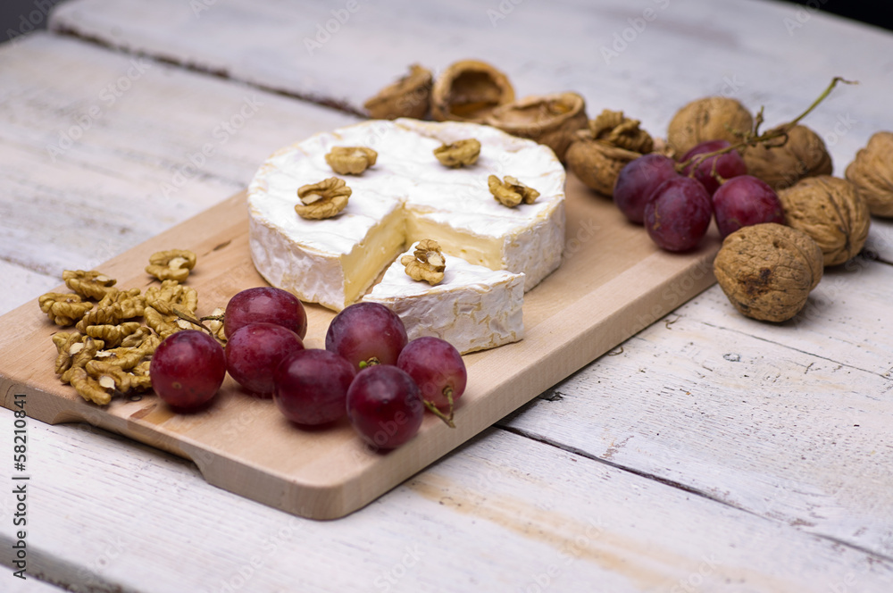cheese, walnuts, grapes, on a chopping board on an old table