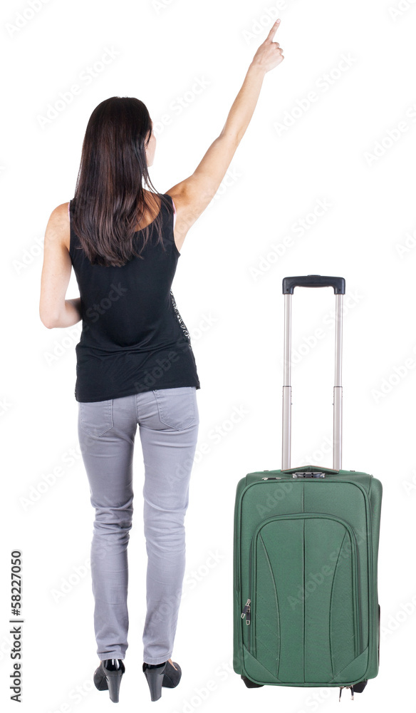 Back view of young brunette woman traveling with suitcas and poi Back view of young brunette woman traveling with suitcas and poi