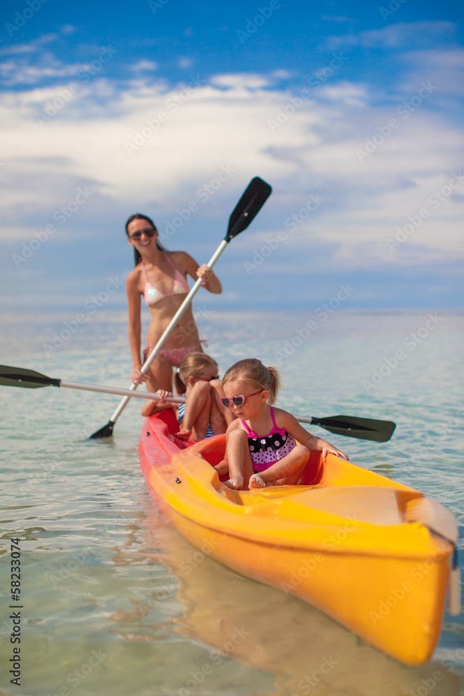 Two little girl and young mother kayaking at blue warm sea