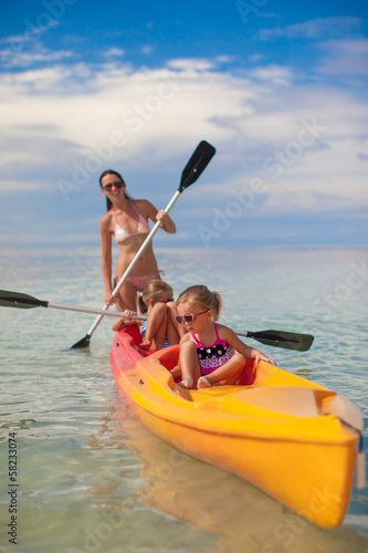 Two little girl and young mother kayaking at blue warm sea