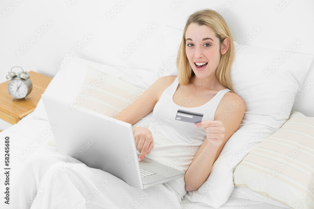 Astonished young woman using her laptop for home shopping while Astonished young woman using her laptop for home shopping while