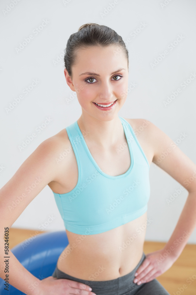 Fit woman sitting on exercise ball in fitness studio Fit woman sitting on exercise ball in fitness studio