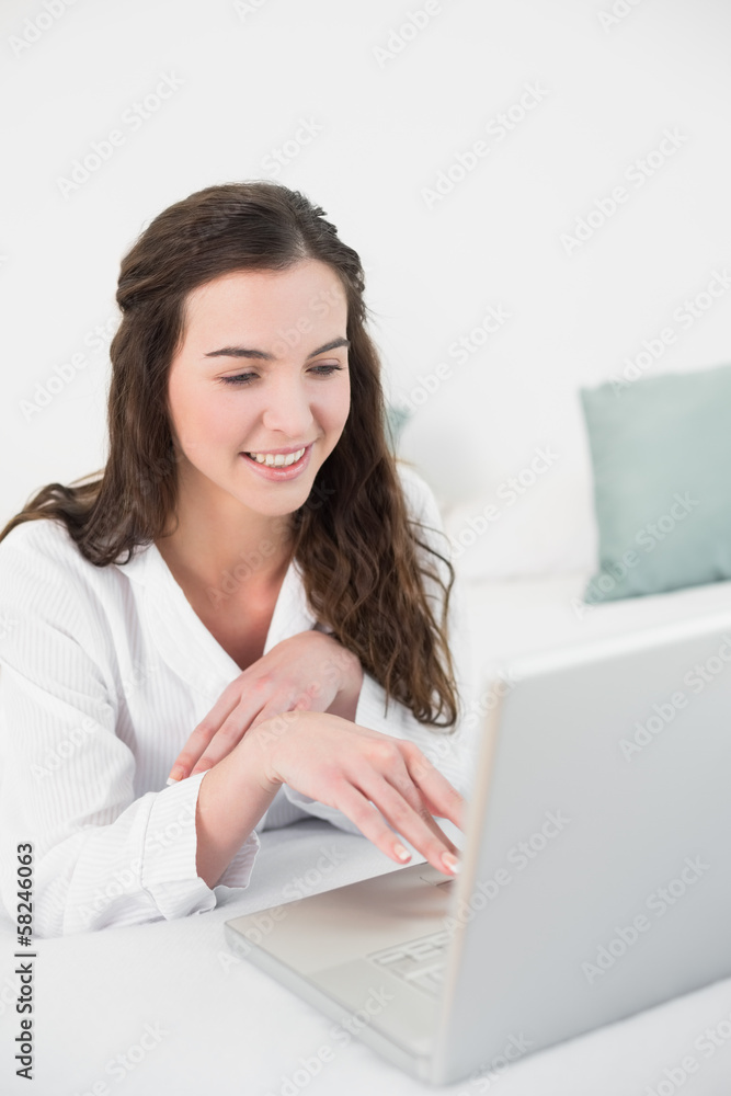Relaxed smiling casual brunette using laptop in bed Relaxed smiling casual brunette using laptop in bed