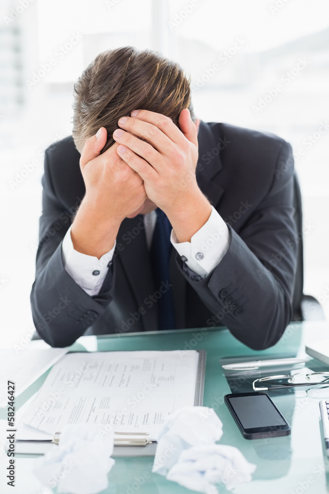 Worried businessman with head in hands at office desk Worried businessman with head in hands at office desk