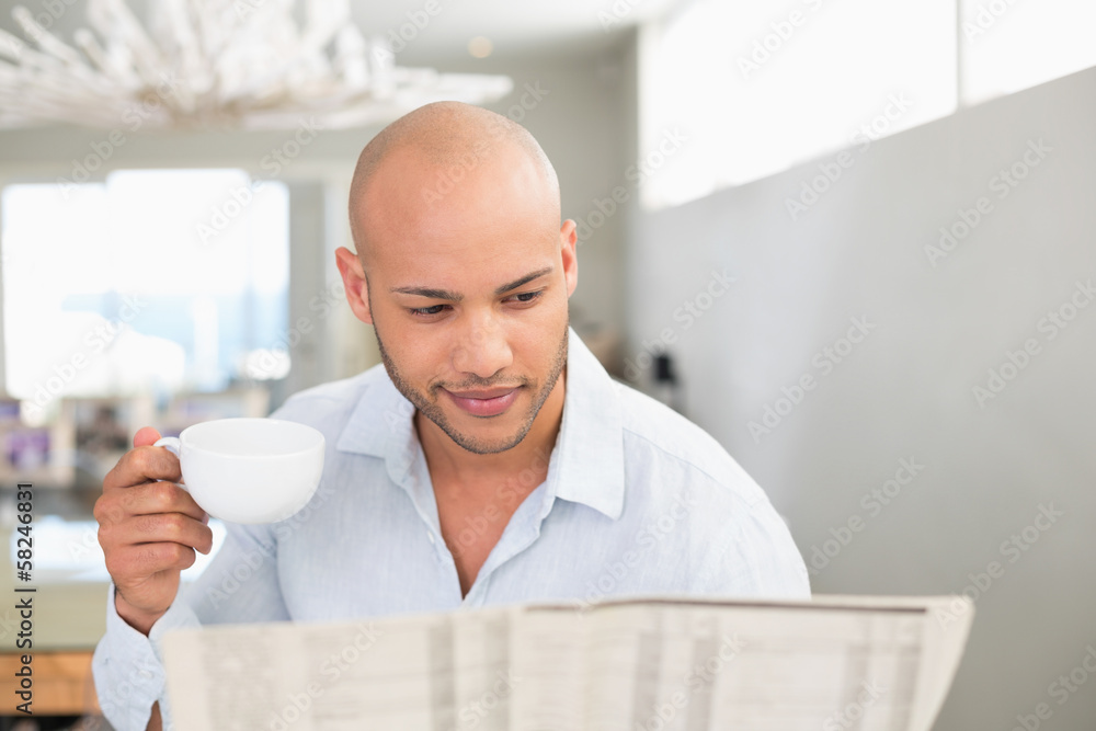 Man having coffee while reading newspaper at home