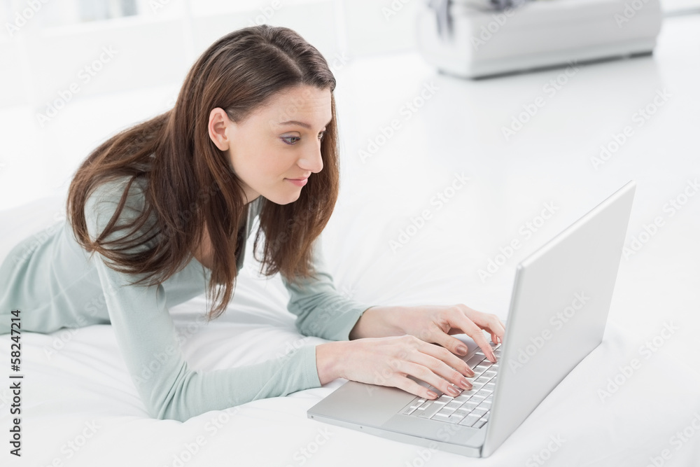 Relaxed casual young woman using laptop in bed Relaxed casual young woman using laptop in bed