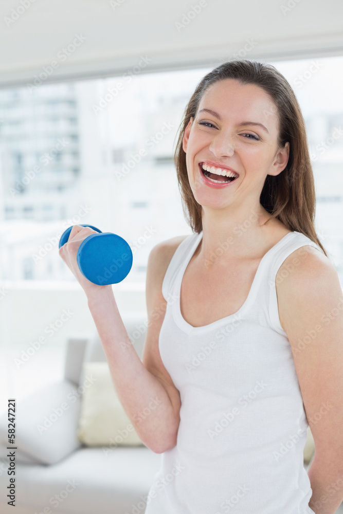Fit woman exercising with dumbbell in fitness studio