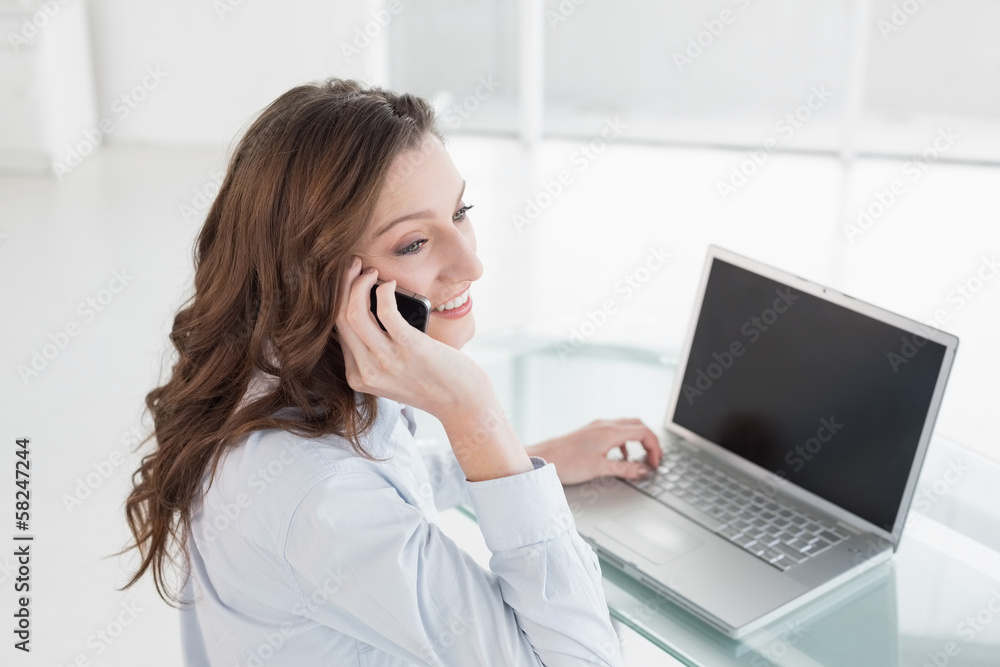 Businesswoman using laptop and cellphone in office Businesswoman using laptop and cellphone in office