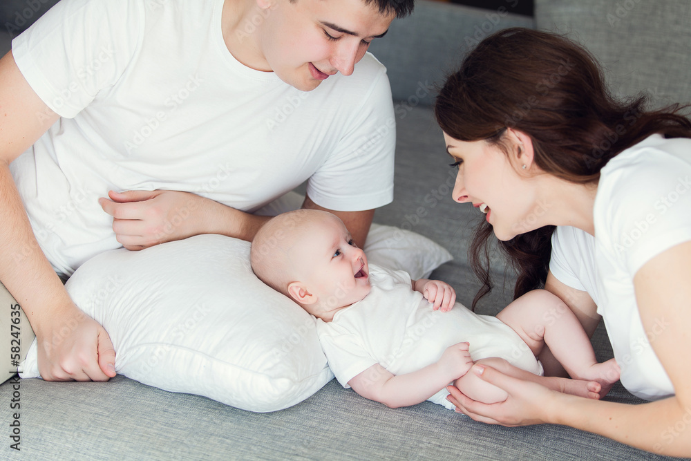mother and father playing with their cute baby on at home