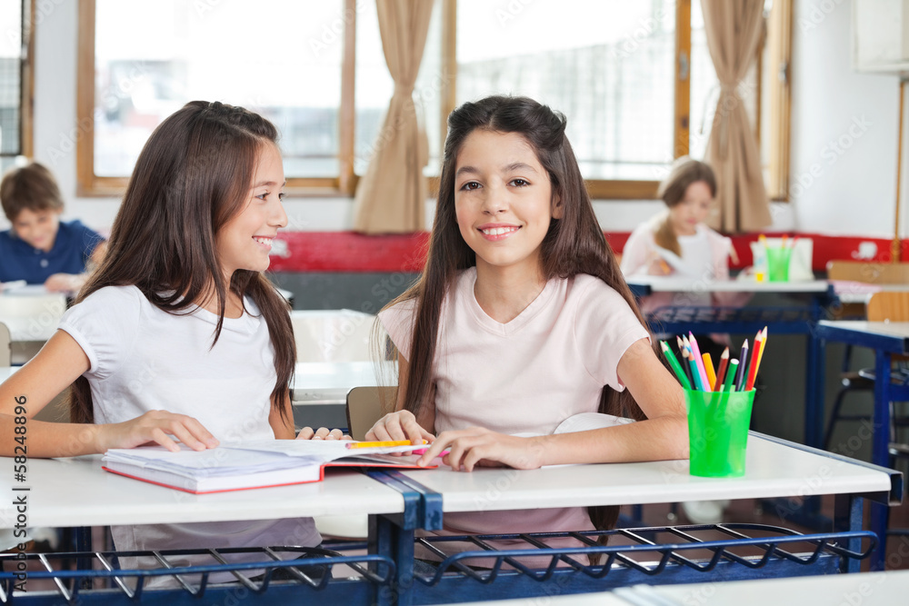 Schoolgirl Sitting With Classmate Looking At Her Schoolgirl Sitting With Classmate Looking At Her